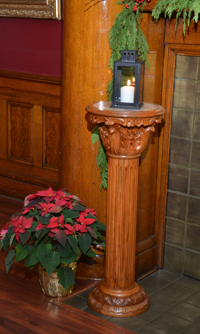 Burning candle on Corinthian column near the fireplace in the Fireplace banquet room at The Corinthian Event Center.