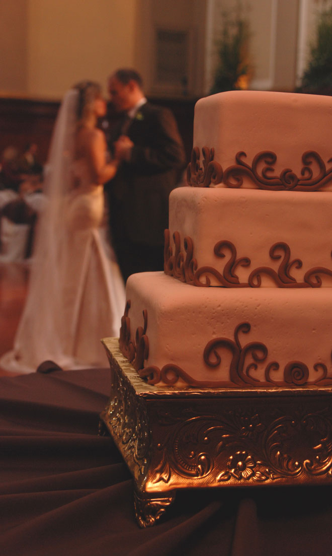 Bride and Groom in dance in Grand Ballroom behind wedding cake at The Corinthian Event Center.