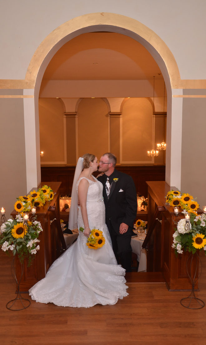 Bride and Groom kiss in the third floor stairway to mezzanine at The Corinthian Event Center.