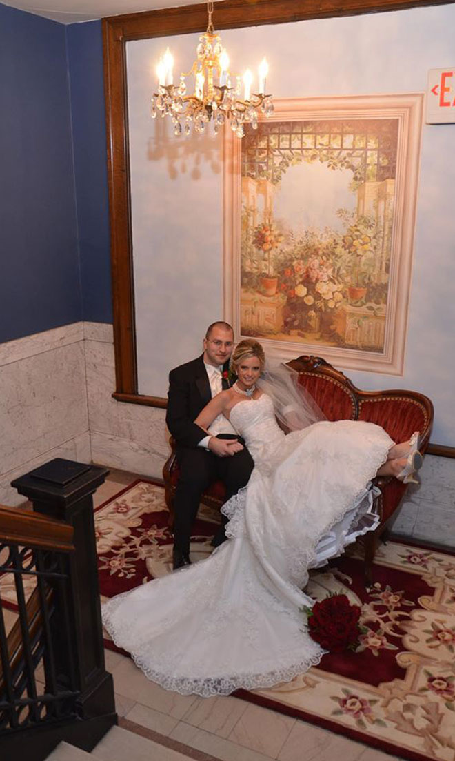 Bride and Groom on red sofa in blue marble entrance at The Corinthian Event Center.