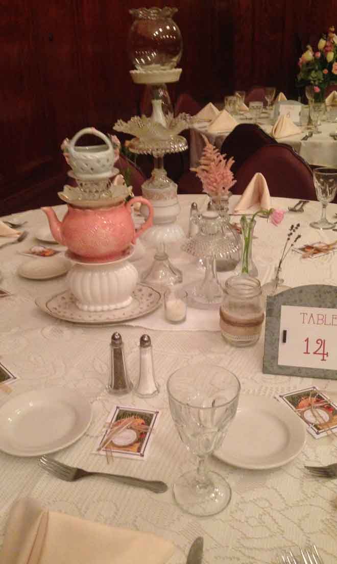 One table setup with white place settings an tepot decor centerpiece at The Corinthian Event Center.