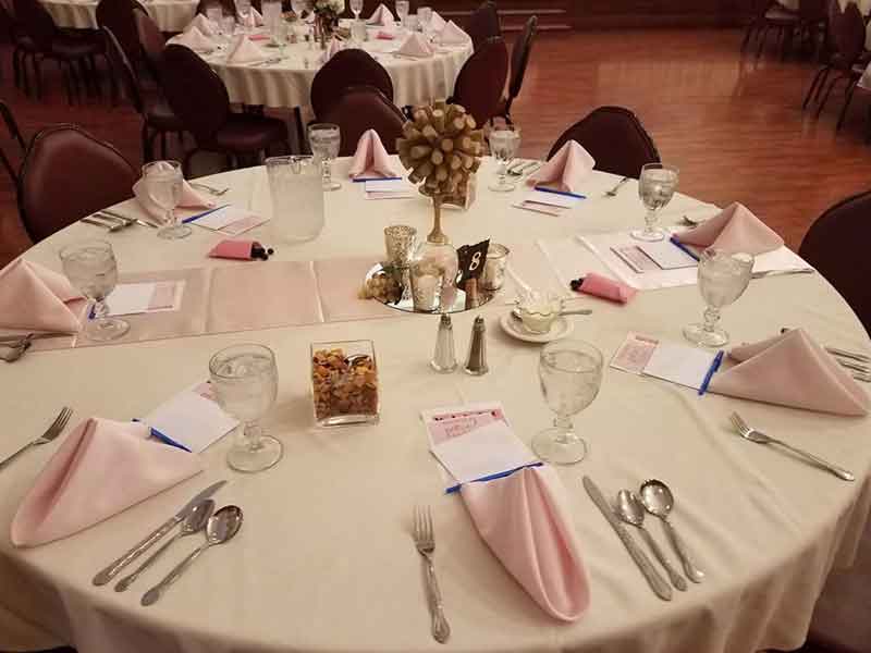 Corporate table place settings in white and pink theme at The Corinthian Event Center.