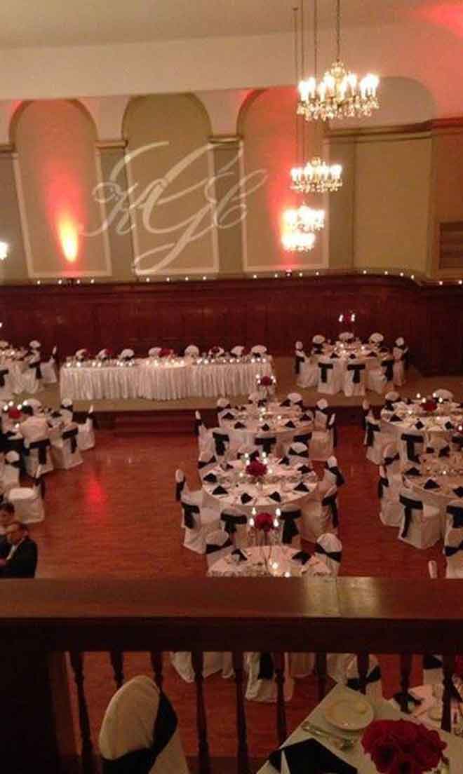 Grand Ballroom setup in black and white theme with chair covers, flower decor centerpieces, and white plate place settings at The Corinthian Event Center.