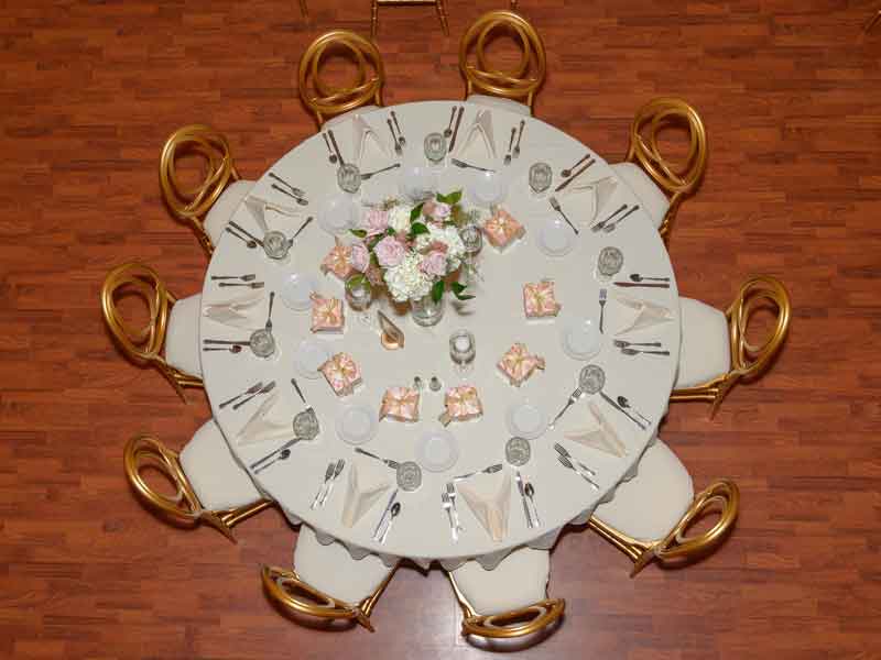 One table setup in white and peach theme with flower centerpieces, and white place settings at The Corinthian Event Center.